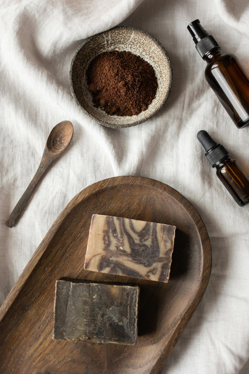 Mediterranean sea salt soap bar with wooden tray and natural ingredients on white cloth, including bowls of sea salt and essential oil bottles.