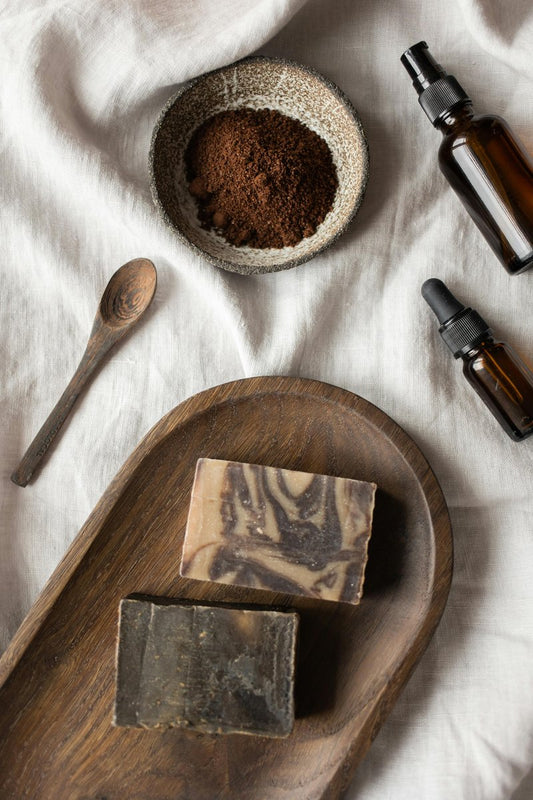 Mediterranean sea salt soap bar with wooden tray and natural ingredients on white cloth, including bowls of sea salt and essential oil bottles.